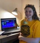 smiling student sitting at a desk while attending a virtual conference for Phi Theta Kappa